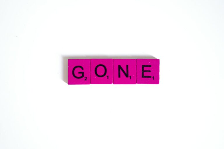 Pink scrabble tiles spelling 'gone' against a clean white background, symbolizing absence.