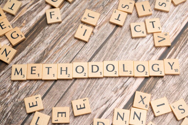 Wooden letter tiles spelling 'methodology' on a textured wooden surface, emphasizing research.