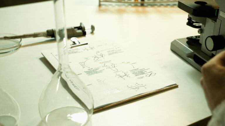Close-up of a laboratory setup with documents, beaker, and microscope on a table.